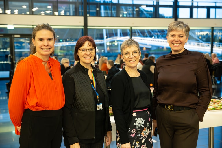 Fire kvinner står oppstilt sammen med universitetet i bakgrunnen.